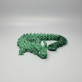 Green dragon 3D print on a blue printing surface with a blurred background