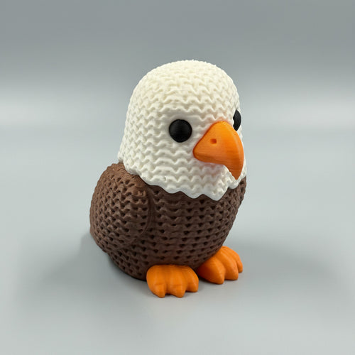 Knitted eagle figurine on a blue surface with a blurred background